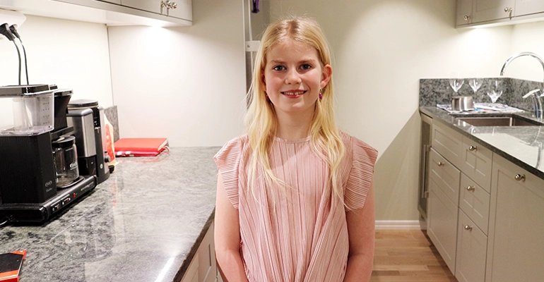 Visar ung flicka med ros tröja i ett kök
