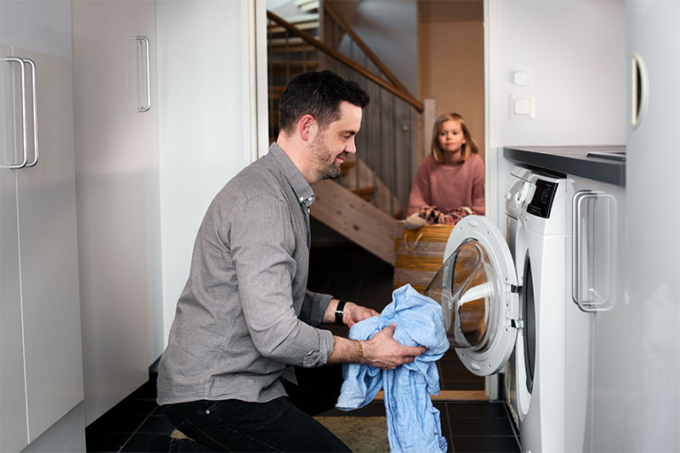 En man fyller tvätt i en tvättmaskin